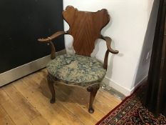 A walnut open armchair in George II style, early 20th century, with shaped cartouche back above an