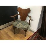 A walnut open armchair in George II style, early 20th century, with shaped cartouche back above an