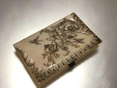 A carved ivory notecase, c. 1900, the cover in relief with dragonflies and a floral spray,