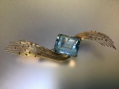 A striking vintage aquamarine brooch, the emerald-cut stone claw set between two yellow metal sprays