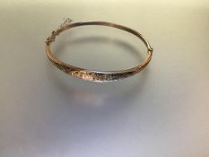 An Edwardian 9ct gold hinged bangle, of tapering form, engraved to the front with floral scrollwork,