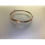 An Edwardian 9ct gold hinged bangle, of tapering form, engraved to the front with floral scrollwork,