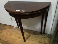 A George III style mahogany fold-over tea table, the hinged semi-elliptical top raised on square