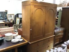 A 19th century pine press cupboard, the pair of arched panel doors enclosing two shelves, with three