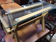 A modern oak framed desk, the rectangular glass top supported on an X-frame trestle base (72 x 120 x