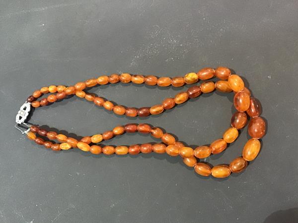 A double strand of amber coloured graduated beads with metal clasp (52g)