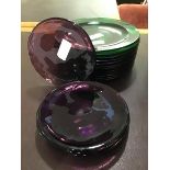Thirteen green glass plates together with six amethyst coloured glass plates