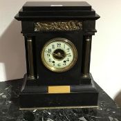 A black marble mantle clock, the rectangular stepped top with inset bronze panels depicting