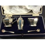 A cased three piece Mappin & Webb Birmingham silver condiment set, with blue glass liners,