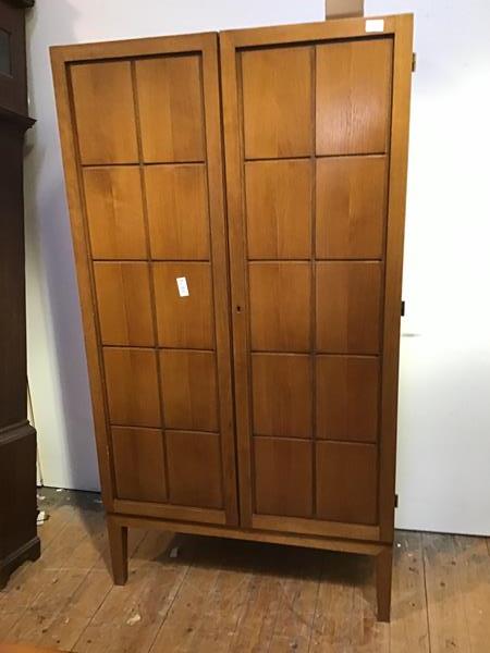 A 1960s oak wardrobe, with a pair of geometric doors enclosing shelves and a pair of drawers, raised