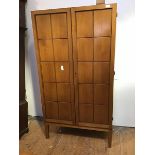 A 1960s oak wardrobe, with a pair of geometric doors enclosing shelves and a pair of drawers, raised