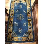 A Chinese wool rug, the centre panel with floral medallions, multiple flowerhead border (177cm x