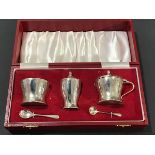 A cased three piece Birmingham silver condiment set, with blue glass liners and spoons