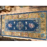 A Chinese wool rug, the centre blue field with allover floral decoration (181cm x 90cm)