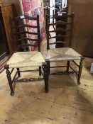 A pair of Edwardian oak ladderback side chairs with rush seats (h.93cm)