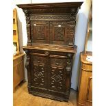 An 18thc carved Oak Revival two part cupboard, the moulded top above a carved frieze, flanked by two