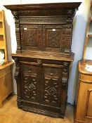 An 18thc carved Oak Revival two part cupboard, the moulded top above a carved frieze, flanked by two