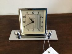 A 1930s chrome bedside clock on rectangular base with adjustable ball feet. (h.9cm)