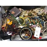 A vintage case containing vintage costume jewellery including pendants, beads, bangles, brooches