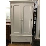 A Victorian style white painted wardrobe, the moulded top with carved frieze above twin panel doors,