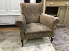 An Edwardian mahogany framed easy chair upholstered in floral moquette raised on squarer tapered