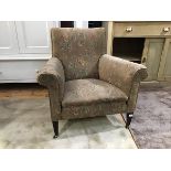 An Edwardian mahogany framed easy chair upholstered in floral moquette raised on squarer tapered