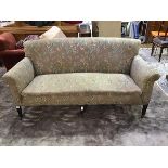 An Edwardian mahogany framed three seater sofa upholstered in floral moquette raised on tapered legs