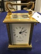 A Mappin & Webb London brass four glass clock, with white enamelled dial and roman numerals,