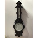 A 19thc/20thc. carved oak banjo style barometer, the carved top above a cased thermometer, with