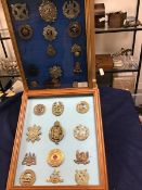 A collection of British Military badges in two glazed frames including Scottish, Canadian, helmet