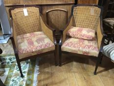 A pair of 1920s mahogany library style chairs, with sweeping arms, with canework back and sides