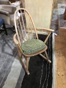 An Ercol beech spindle back rocking chair, blue label to rear of seat, with pop on pad cushion (h.