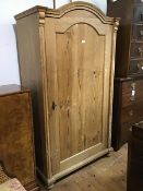 A Continental pitch pine Armoire, the arched top above a panel door, with plain sides, on moulded