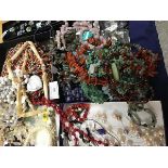 A mixed lot of beads and necklaces including a red hardstone necklace with yellow metal clasp marked