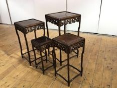 A quartetto set of Chinese hardwood tables, each with recessed top above a pierced foliate frieze,