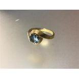 A single stone sapphire ring, the round-cut pale blue stone claw set on textured shoulders, on a