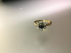 A sapphire and diamond flowerhead cluster ring, the central round-cut sapphire claw-set within a