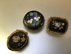 A group of three 19th century brooches, one oval, the floral pietra dura panel within a gilt metal