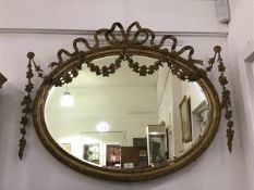 An Edwardian giltwood wall mirror c.1900, the oval plate within a moulded frame embellished with
