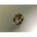 A ruby and diamond-set yellow metal serpent ring, stamped "18", of three coils, the head with a