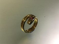 A ruby and diamond-set yellow metal serpent ring, stamped "18", of three coils, the head with a