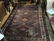 A Caucasian rug, the madder field with four hooked ivory lozenges and blue guard bands.