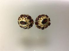 A pair of garnet cluster earrings, each oval, centred by an oval-cut stone within a band of ten