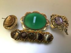 A group of four 19th century brooches comprising: one centred by an oval stone of amethyst colour in