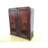 A scarlet lacquered table cabinet, c. 1920 in the manner of Liberty & Co., the arched top above a