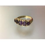 A five stone amethyst ring, the graduated oval-cut stones on a scroll-cast and engraved mount, on an