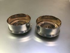 A pair of silver bottle coasters, Douglas Pell, London 1992, plain, each on turned mahogany base.