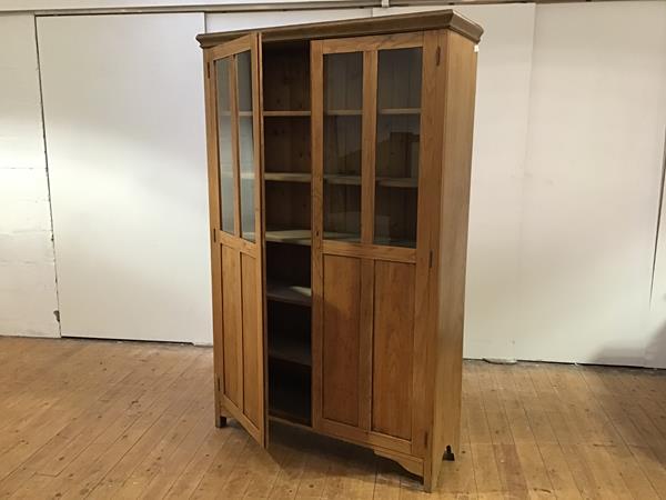 An Edwardian light elm cabinet, the moulded cornice above a pair of glazed doors, enclosing five