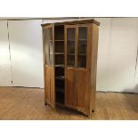 An Edwardian light elm cabinet, the moulded cornice above a pair of glazed doors, enclosing five