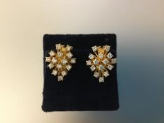 A pair of diamond cluster earrings, each domed setting with fourteen round brilliants claw-set in